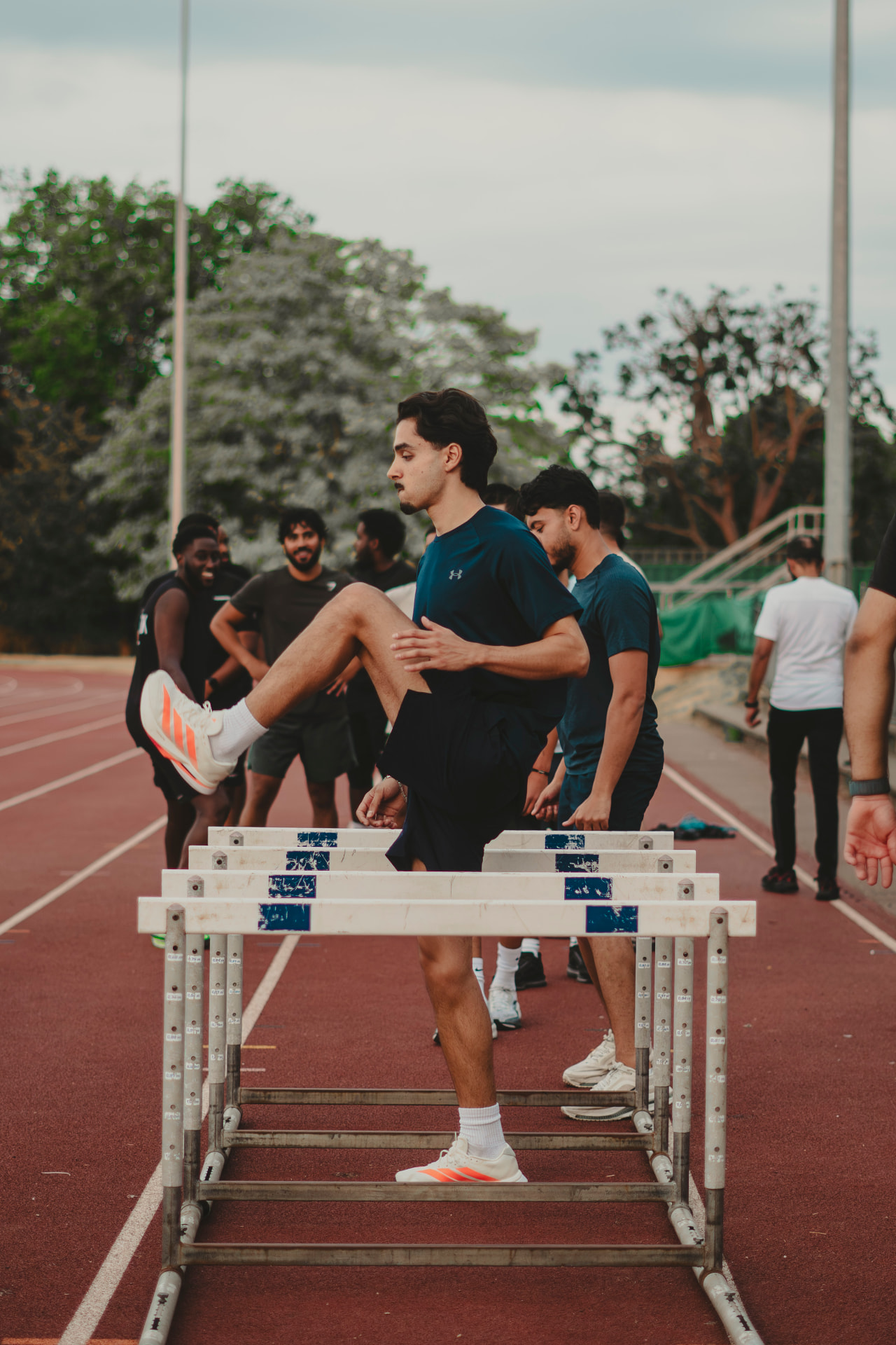 Athletes warming up over hurdles on the track
